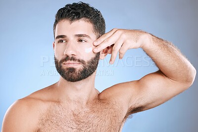 Buy stock photo Face, cream and man serious for skincare, sunscreen product and clean wellness on blue background. Male model, facial lotion and body cosmetics for natural beauty, studio aesthetics or self care glow