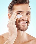 Skincare, face and man with eye patch in studio isolated on a blue background. Beauty, portrait and male model with  pad product for dermatology, cosmetics and facial treatment, wellness and health.