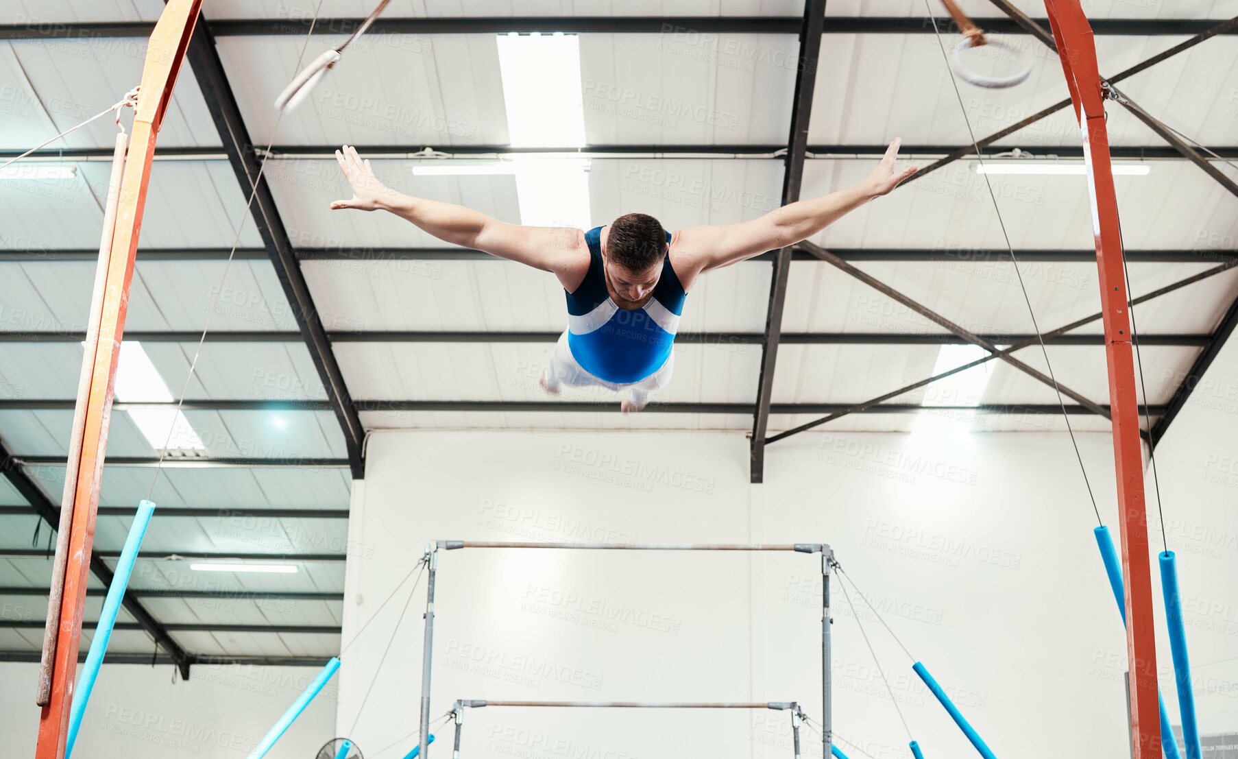 Buy stock photo Man, acrobat and gymnast flying off rings in fitness for practice, training or workout at gym. Professional male in gymnastics or performance for athletics, acrobatic or strength and balance exercise