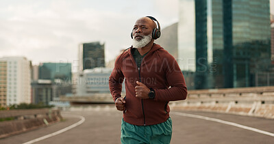 Buy stock photo Running, city and senior man with headphones in training, streaming music and fitness. Retirement, black person or wellness of african runner for race in progress, urban road or marathon competition