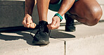 Hands, tie and footwear with a sports person on steps in the city, getting ready for a running workout. Fitness, exercise and a runner or athlete training closeup in an urban town to improve health