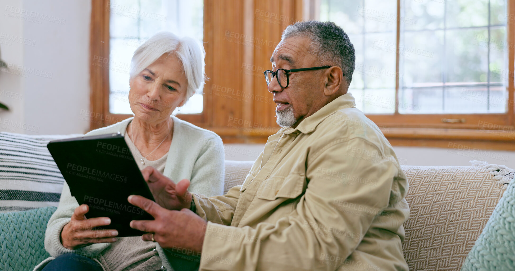 Buy stock photo Tablet, love and an elderly couple on a sofa in the living room of their home to search social media together. Diversity, app or technology with a senior man and woman in the apartment for retirement