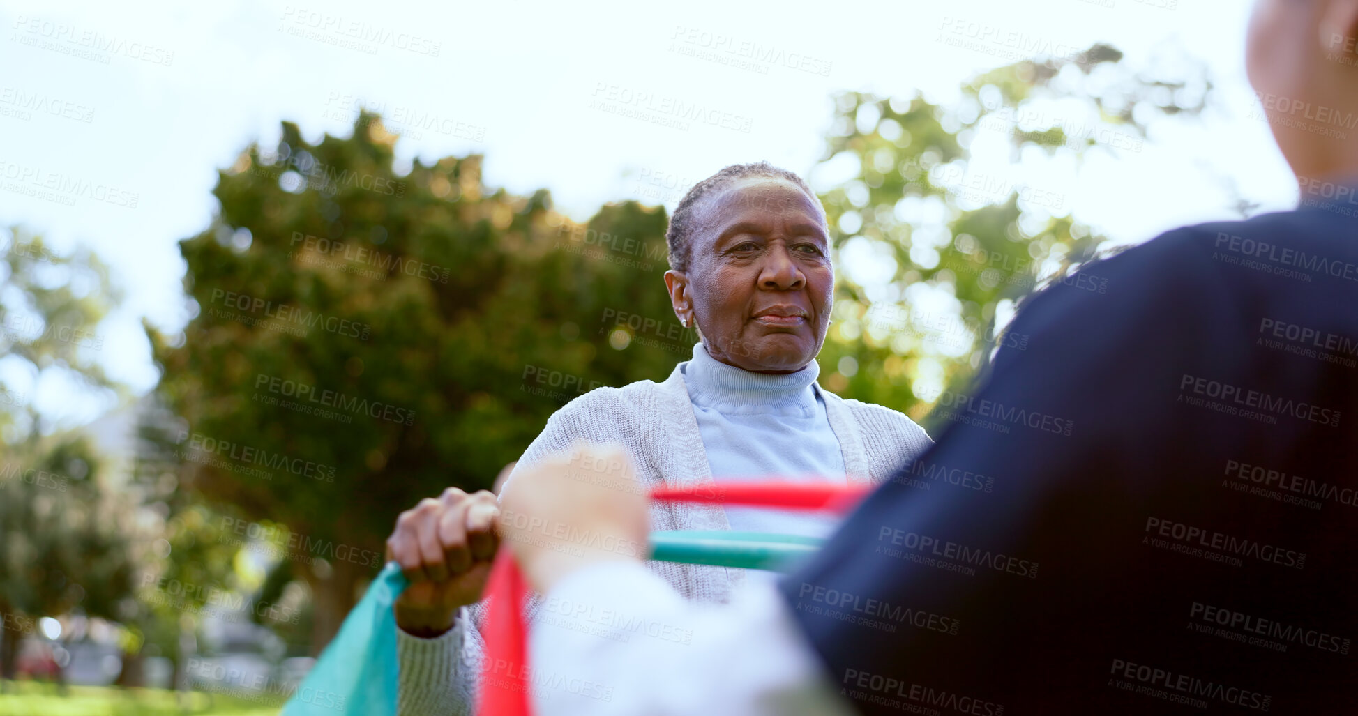 Buy stock photo Senior, woman and nurse with stretching band outdoor for exercise, workout or fitness in a park. People, professional or caregiver or physical activity for physiotherapy, wellness or health in nature