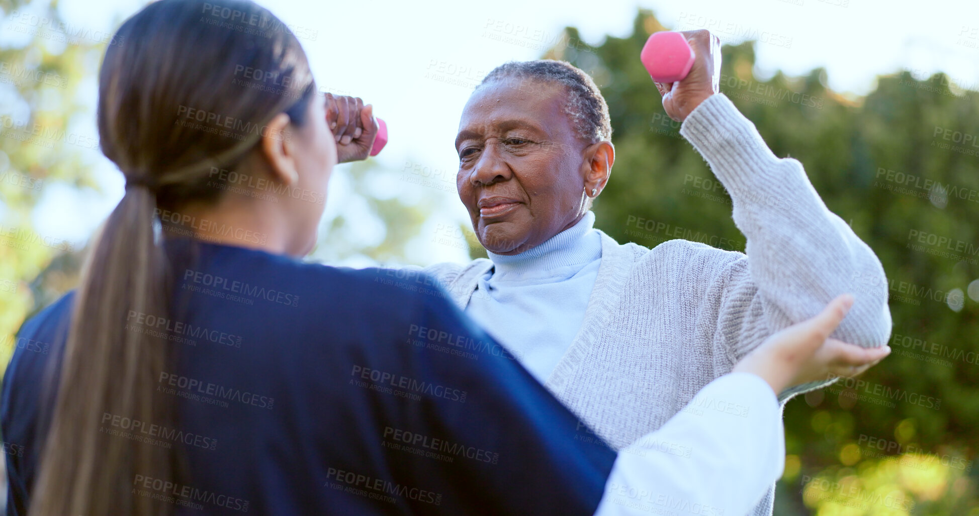 Buy stock photo Dumbbell, fitness and a senior black woman with a nurse outdoor in a garden together for physiotherapy. Exercise, health or wellness with an elderly patient and volunteer in the yard to workout