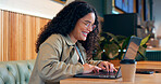 Happy woman in coffee shop, typing on computer and remote work, reading email or writing blog, article or search on internet. Laptop, freelancer and copywriting in cafe, smile at restaurant or table