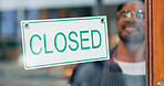 Happy man, small business or closed sign on window in coffee shop or restaurant for end of service. Closing time, smile or manager with board, poster or message in retail store or cafe for notice