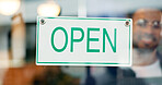 Storefront, small business or open sign on window in coffee shop or restaurant for service or advertising. Man, portrait or entrepreneur holding board, poster or welcome for message in cafe or diner
