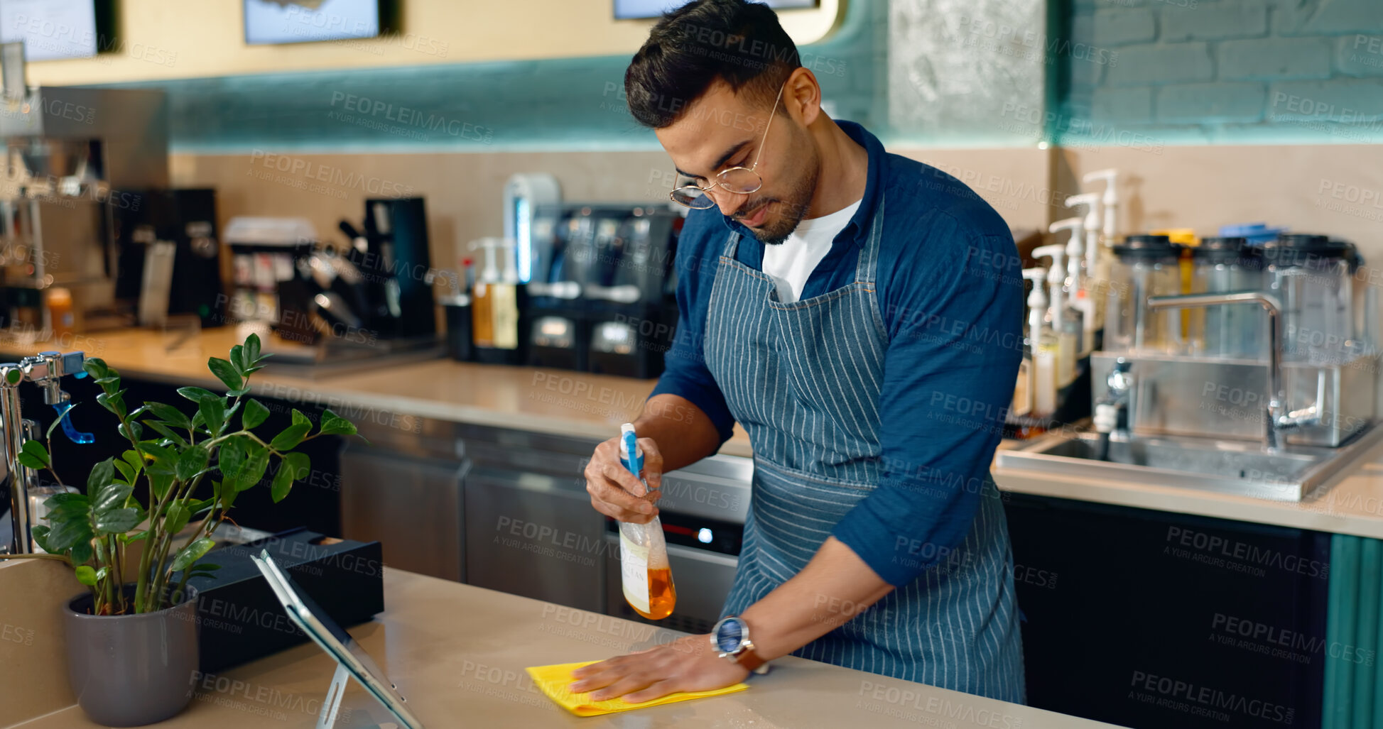 Buy stock photo Waiter, man and cleaning table in cafe for dust, bacteria and dirt with cloth, spray or detergent. Barista, person or wipe wooden furniture in coffee shop or restaurant with chemical liquid for shine