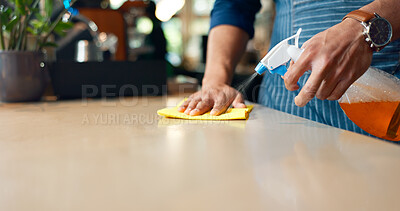Waiter, hands and cleaning table in restaurant for dust, bacteria and dirt with cloth, spray or detergent. Barista, person or wipe wooden furniture in coffee shop or cafe with chemical liquid closeup