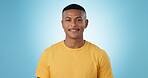 Happy, smile and portrait of man in a studio with positive, good and confident attitude. Happiness, model and young male person with casual, trendy and cool style with tshirt by blue background.