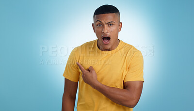 Buy stock photo Pointing, shock and portrait of man in a studio with mockup for marketing, advertising or promotion. Surprise, wow and young male person with a show hand gesture isolated by blue background.