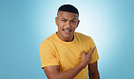 Pointing, smile and portrait of man in a studio with mockup for marketing, advertising or promotion. Happy, positive and young male person with a show hand gesture isolated by blue background.