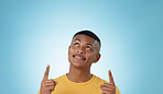 Man, space and pointing up in studio for advertising choice, decision and information about us on blue background. Face, model and thinking to show presentation of mockup, promotion and announcement 