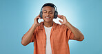 Music, calm man and dancing with headphones and studio with radio and audio app with blue background. Tech, smile and sound with relax African male person with web media streaming and hearing a song