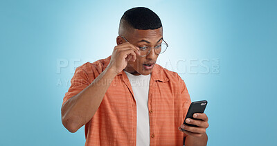 Buy stock photo Surprise, glasses and man with smartphone, internet and reaction with expression on a blue background. Person, guy and model with a cellphone, email and announcement with post, blog and digital app