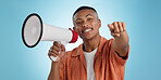 Man, megaphone and choice or pointing you for announcement, broadcast and choice or news on blue background. Portrait of person for join us, attention and voice with sale, bonus or winning in studio