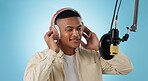 Artist man, headphones and mic in studio with thinking, ideas and creativity for song by blue background. Musician, person and microphone with recording, production and performance with singing voice