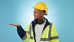 Construction worker, smile and portrait with hand advertising, promotion or mockup in blue background. Happy, face and builder show safety announcement, presentation or branding space in studio