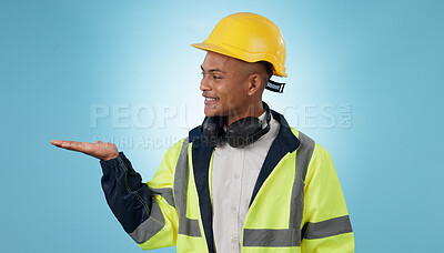 Buy stock photo Construction worker, smile and with hand for advertising, promotion or mockup in blue background. Happy, face and builder show safety announcement, presentation or choice with space in studio