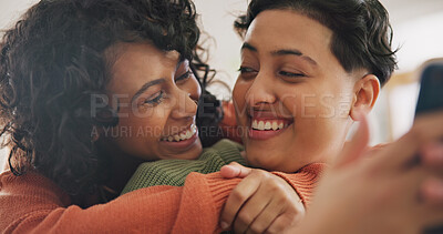 Phone, hug and an lgbt couple laughing together in their home while browsing a social media app. Gay, love and comedy with happy lesbian women looking at memes on a mobile for fun or romantic bonding