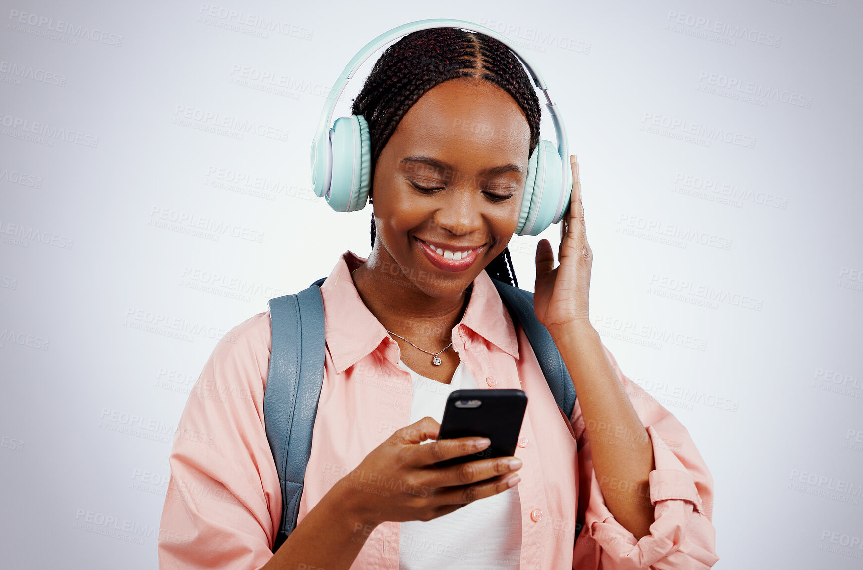 Buy stock photo Woman, student and headphones on mobile for music, elearning audio and education on a white background. Happy african person in backpack and electronics for listening or streaming on phone in studio