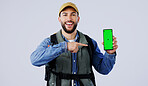 Happy man, backpack and pointing to phone green screen on mockup or hiking app against a studio background. Portrait of male person or hiker smile and showing mobile smartphone display or travel tips