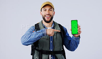 Happy man, backpack and pointing to phone green screen on mockup or hiking app against a studio background. Portrait of male person or hiker smile and showing mobile smartphone display or travel tips