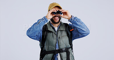 Buy stock photo Hiking, backpack and happy man with binocular search in studio for travel, freedom or adventure on grey background. Camping, journey and backpacker with explore equipment for bird watching in nature