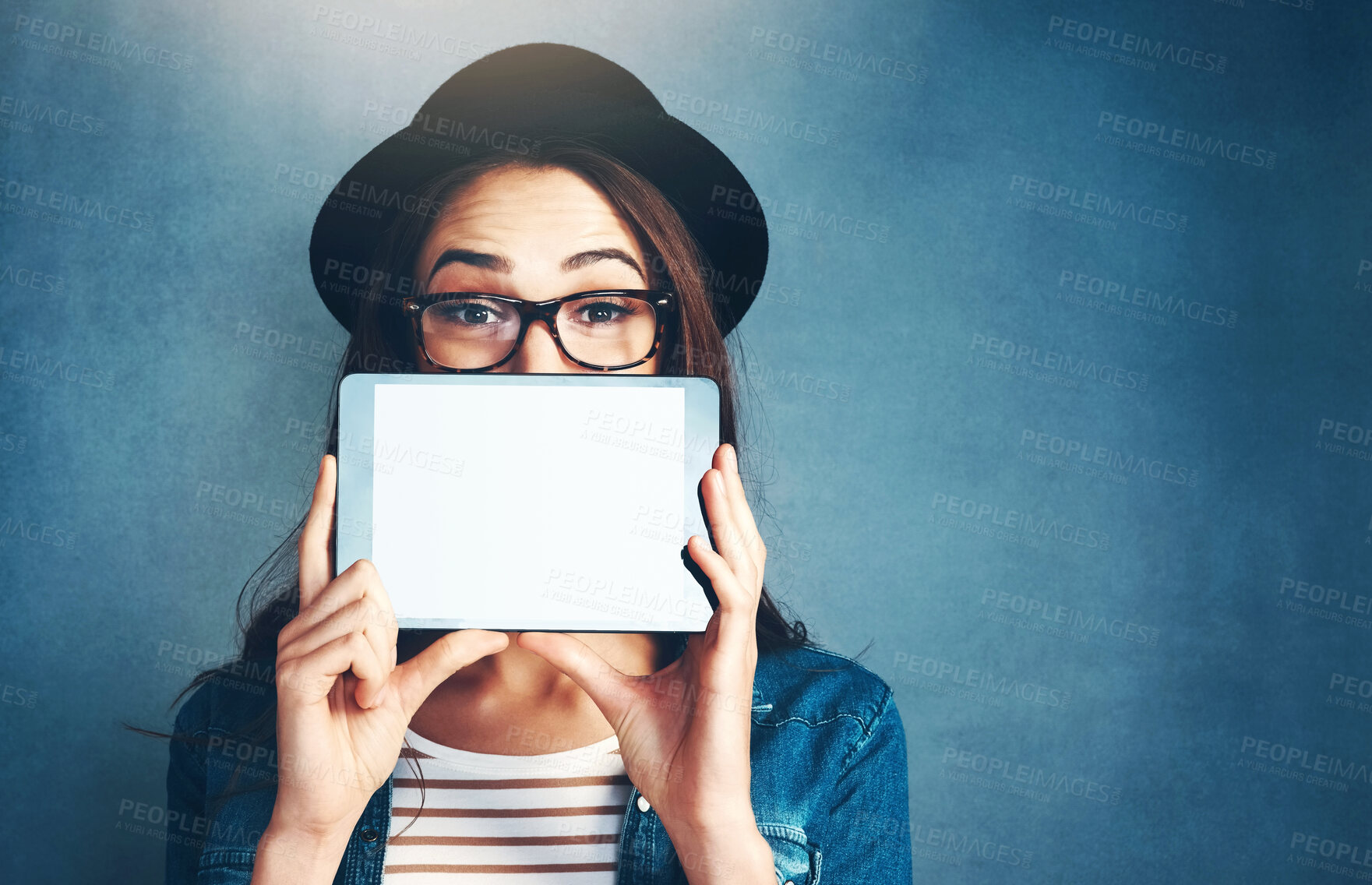 Buy stock photo Portrait, tablet and mockup with a fashion woman in studio on a blue background for social media marketing. Face, display and style with a young person holding an empty screen for advertising space