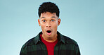 Wow, man and portrait in studio with shocked face for announcement, discount or good news on mock up space. Person, surprised or emoji for secret, gossip or surprise with big eyes on blue background
