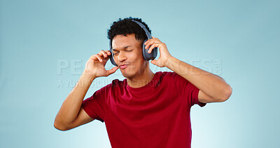 Buy stock photo Man, headphones and dancing with music in studio for mock up of streaming service on blue background. Cape Town, male model and eyes closed for listening to song, podcast or radio in space with promo