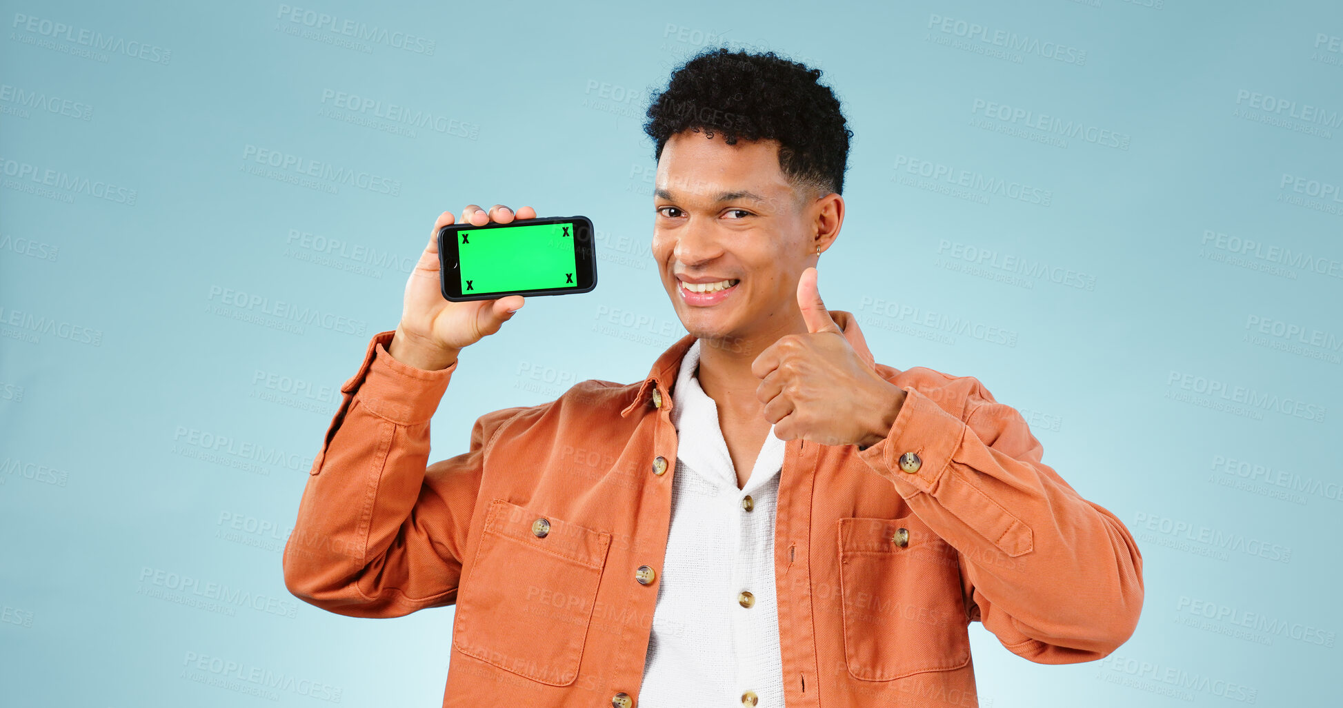 Buy stock photo Thumbs up, green screen phone and portrait of man on blue background for promotion, approval or thank you. Emoji, social media and person with hand sign for agreement, mobile app or website in studio