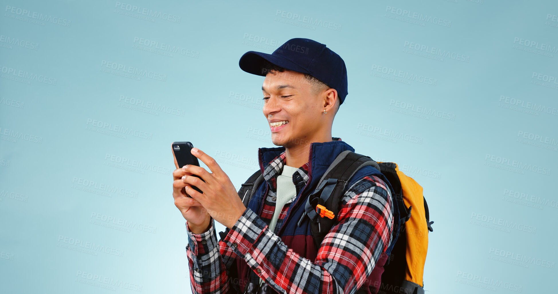 Buy stock photo Hiking, smile and typing with man, cellphone and adventure with social media on blue studio background. Person, hiker and model with a smartphone, mobile user and contact with journey or mockup space