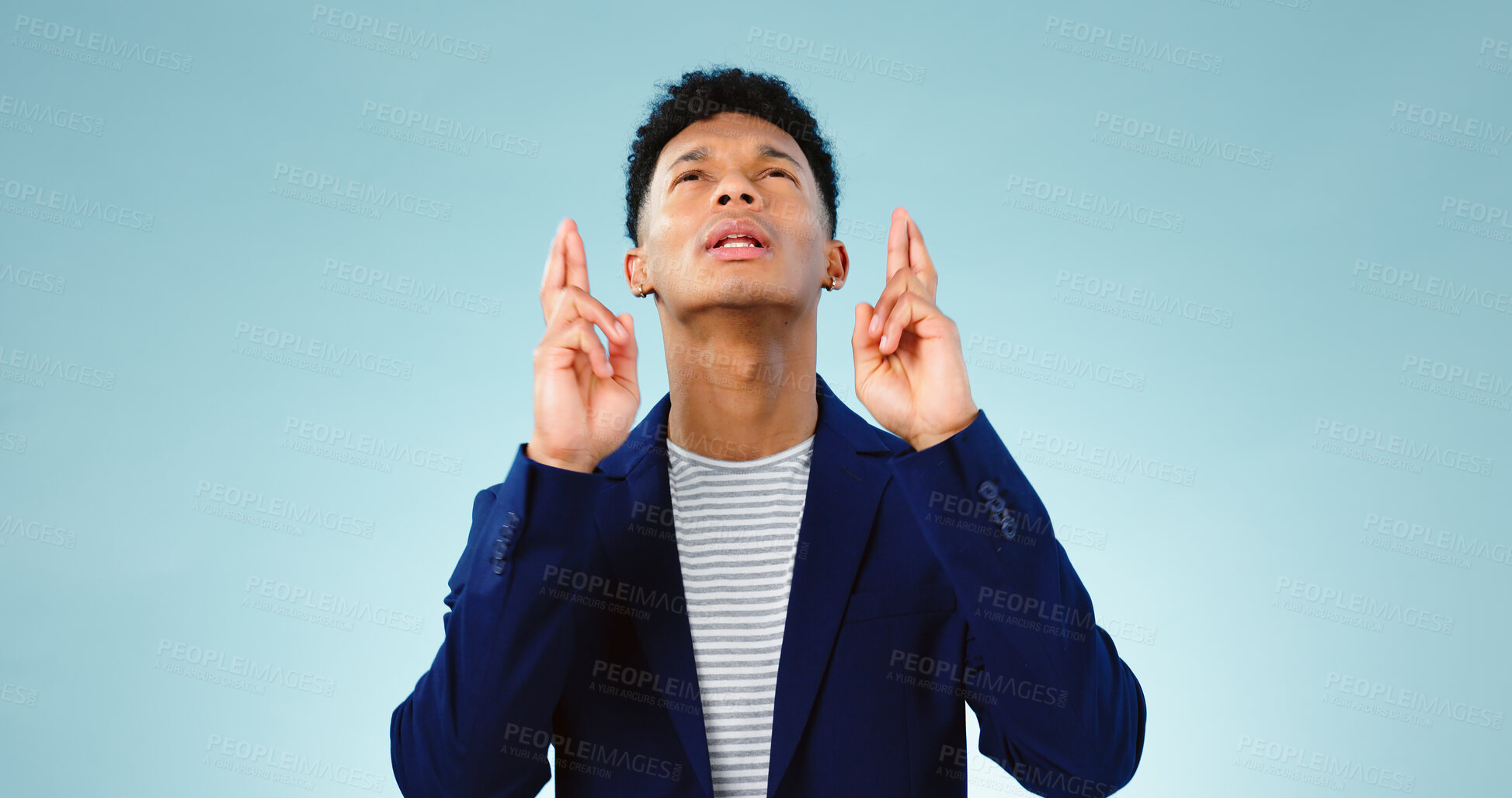 Buy stock photo Man, fingers crossed or good luck in studio for prize, promotion or competition giveaway by blue background. Model, hope and emoji for wish for blessing, nervous and waiting for results in mockup