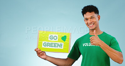 Buy stock photo Man, volunteer and thumbs up with poster in studio on blue background with go green mock up in portrait. Young person, smile or excited for eco friendly, event or recycling in sustainable development