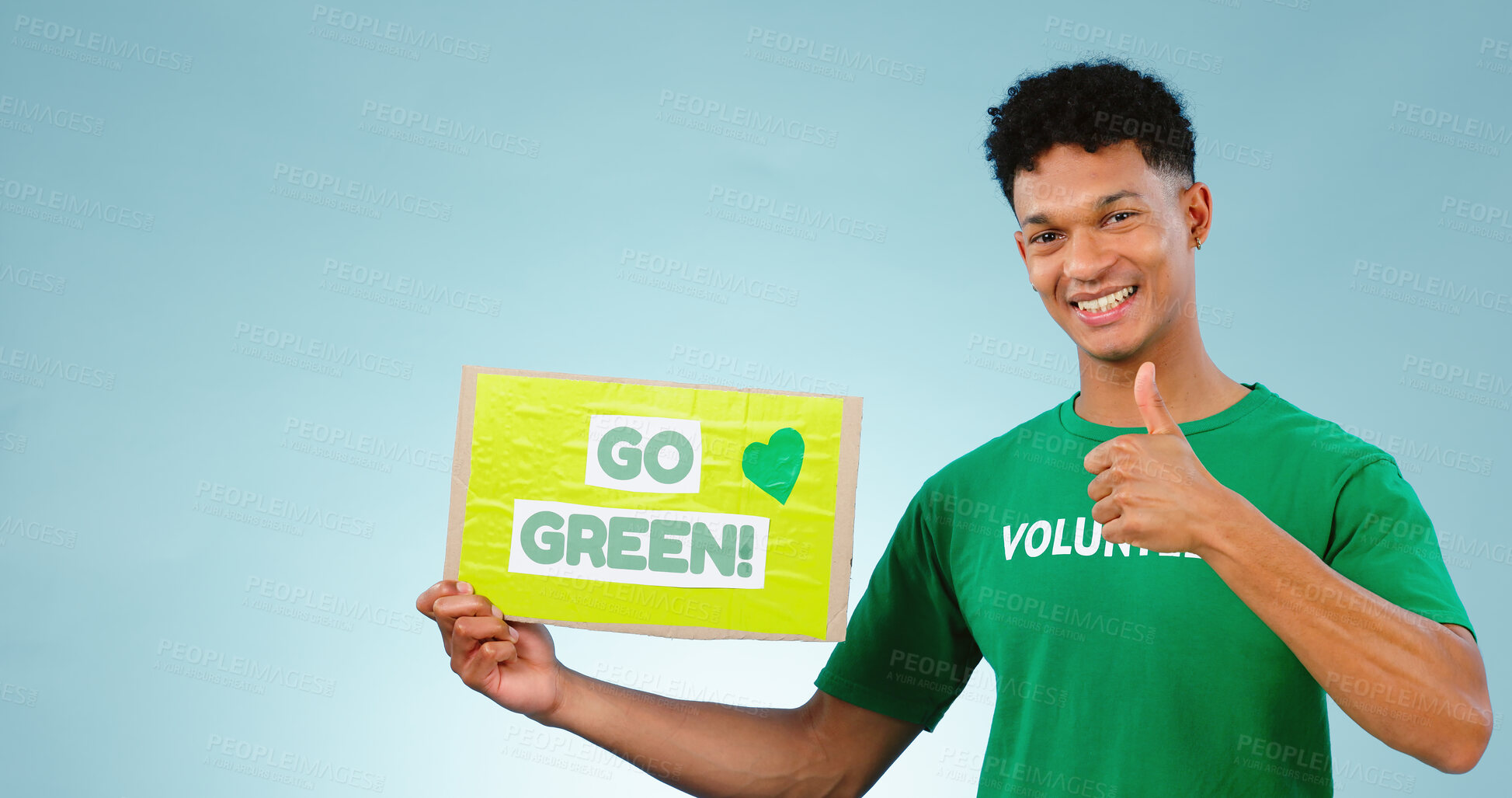 Buy stock photo Man, volunteer and thumbs up with poster in studio on blue background with go green mock up in portrait. Young person, smile or excited for eco friendly, event or recycling in sustainable development