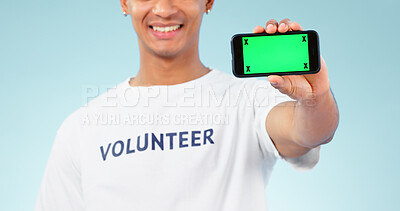 Buy stock photo Hand, phone and green screen with a volunteer man in studio on blue background for marketing or charity. Smile, space or advertising and a person showing chromakey on a display with tracking markers