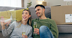 Happy couple, celebration and champagne for moving home or new property, drink in living room. Man, woman and wine glass for achievement in apartment boxes for change or floor chat, cheers at sofa