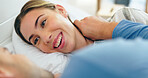 Face, smile and a young couple in bed together to relax or wake up in the morning of a weekend. Trust, romance or happy with a young man and woman closeup in the bedroom of their home for love