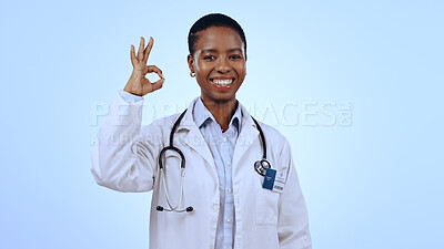 Buy stock photo Portrait, okay or happy black woman doctor with smile or confidence isolated on blue background. Wellness, studio or female African healthcare worker with approval sign, success or yes hand gesture