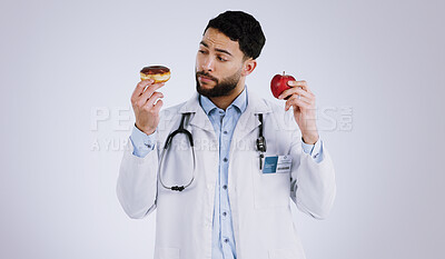 Buy stock photo Doctor, apple or donut for choice in health for nutrition in studio on white background for mock up. Man, male model or medical professional with thinking of diet, food or offer for eating in Mexico