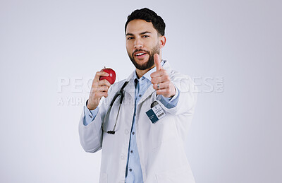 Buy stock photo Happy man, doctor and apple with thumbs up for diet, good health or approval against a gray studio background. Portrait of male person or medical nurse with red organic fruit, like emoji or yes sign