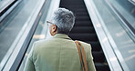Woman, back and travel on escalator in airport, building and thinking about work trip opportunity. Mature, businesswoman and walking with luggage and bag on stairs, steps or entrance in lobby
