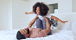 Father, daughter and airplane in bedroom with playing, bonding and freedom for happiness or trust on bed of home. Family, man and girl child with lifting in knees with balance, relationship and love