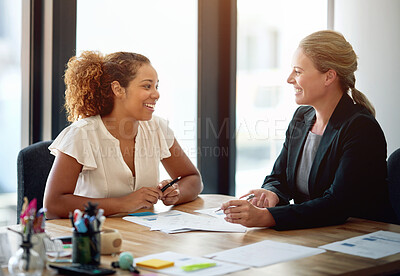 Buy stock photo Shot of two smiling businesswoman sitting in an office talking together