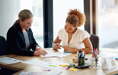 Buy stock photo Shot of two businesswoman sitting in an office discussing paperwork