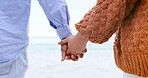 Couple, holding hands and beach for love, care or support in trust, travel or outdoor getaway together. Closeup of man and woman touching in romance for unity, bonding or compassion on ocean coast