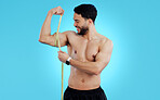 Happy man, measuring tape and bicep in fitness, bodybuilding or weight loss against a blue background. Male person, athlete or bodybuilder smile taking muscle or arm measurement for flex on mockup