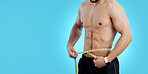 Man, body and tape measure in weight loss, bodybuilding or diet isolated on a blue studio background. Closeup of male person, athlete or bodybuilder measuring waist for workout or results on mockup