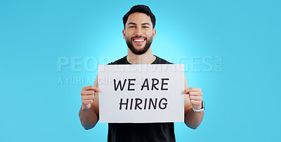 Buy stock photo Portrait, smile and man with we are hiring, poster or announcement in studio on blue background. Recruitment, banner and face of male model with news, announcement or business, opportunity or offer